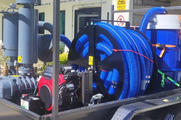 Photo of large coiled blue vacuum hose, trailer mounted as part of the industrial vacuum cleaning equipment